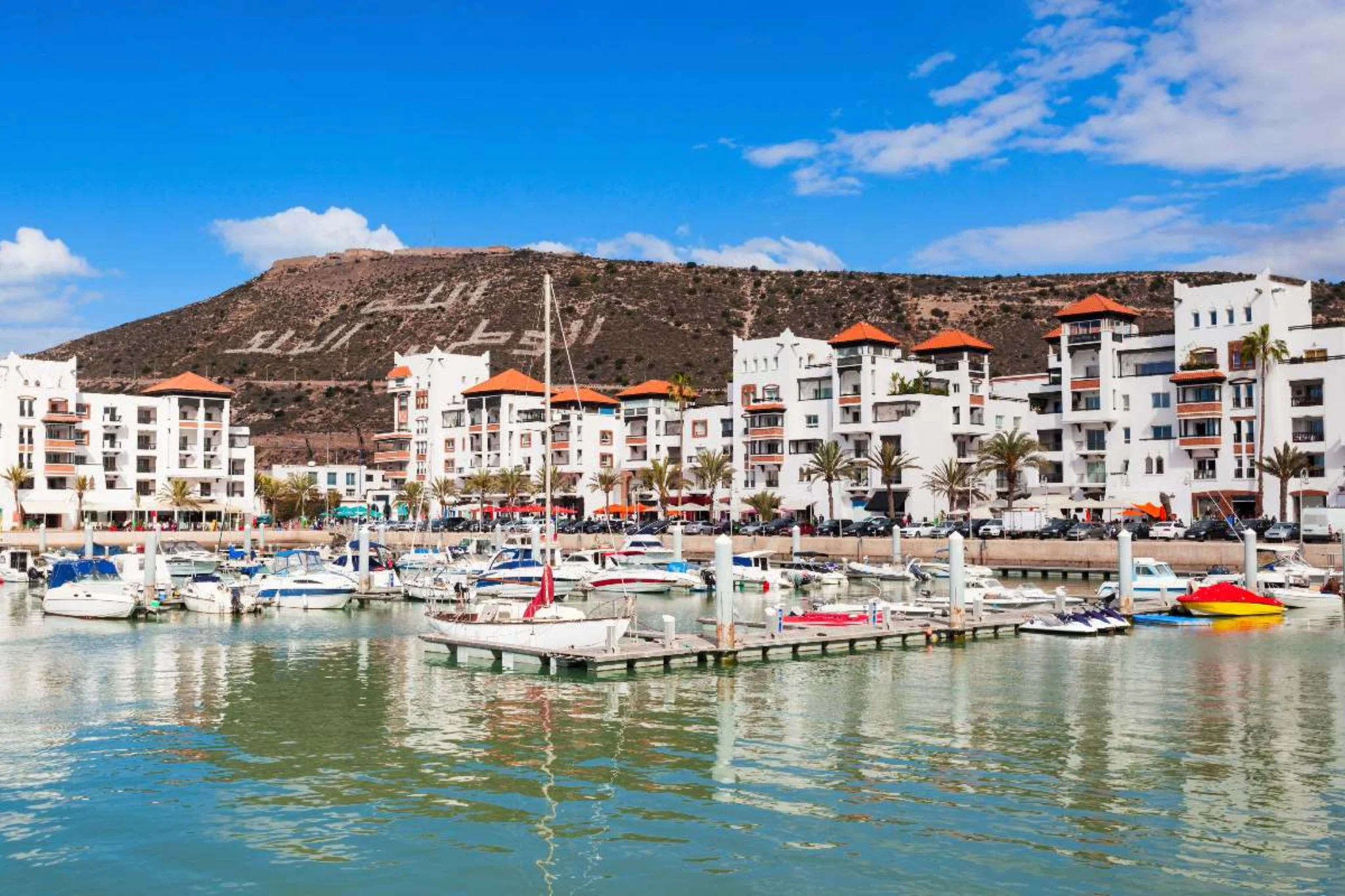 Bateaux amarrés dans un port devant des bâtiments blancs.