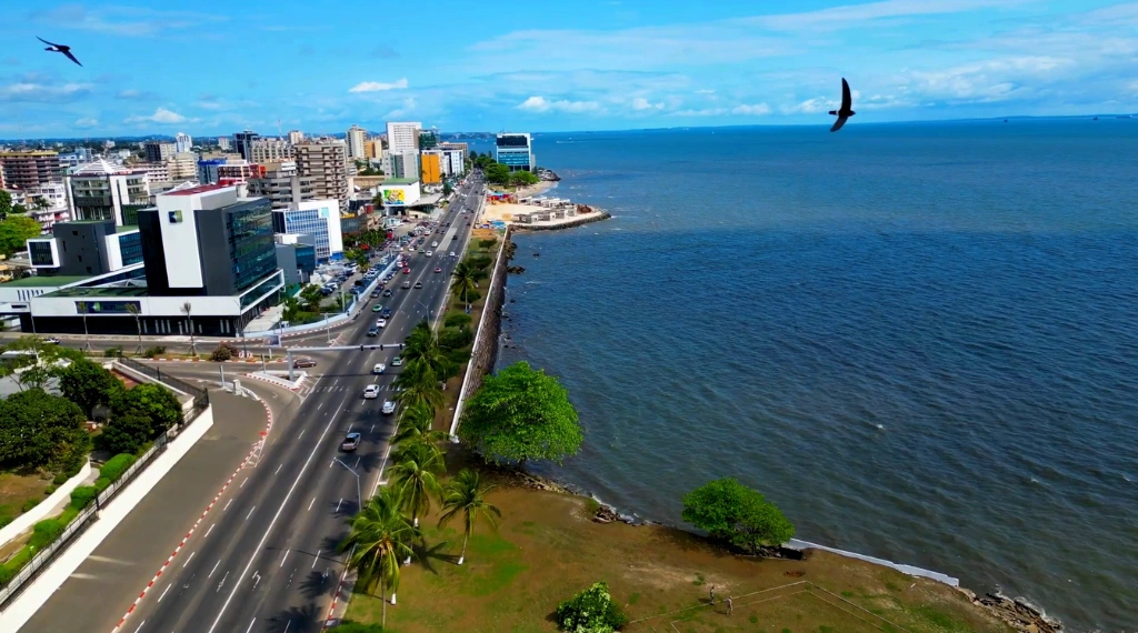 Une route côtière bordée de palmiers longeant l'océan bleu à Libreville.