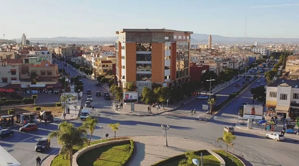 Carrefour urbain avec un grand bâtiment moderne au centre.