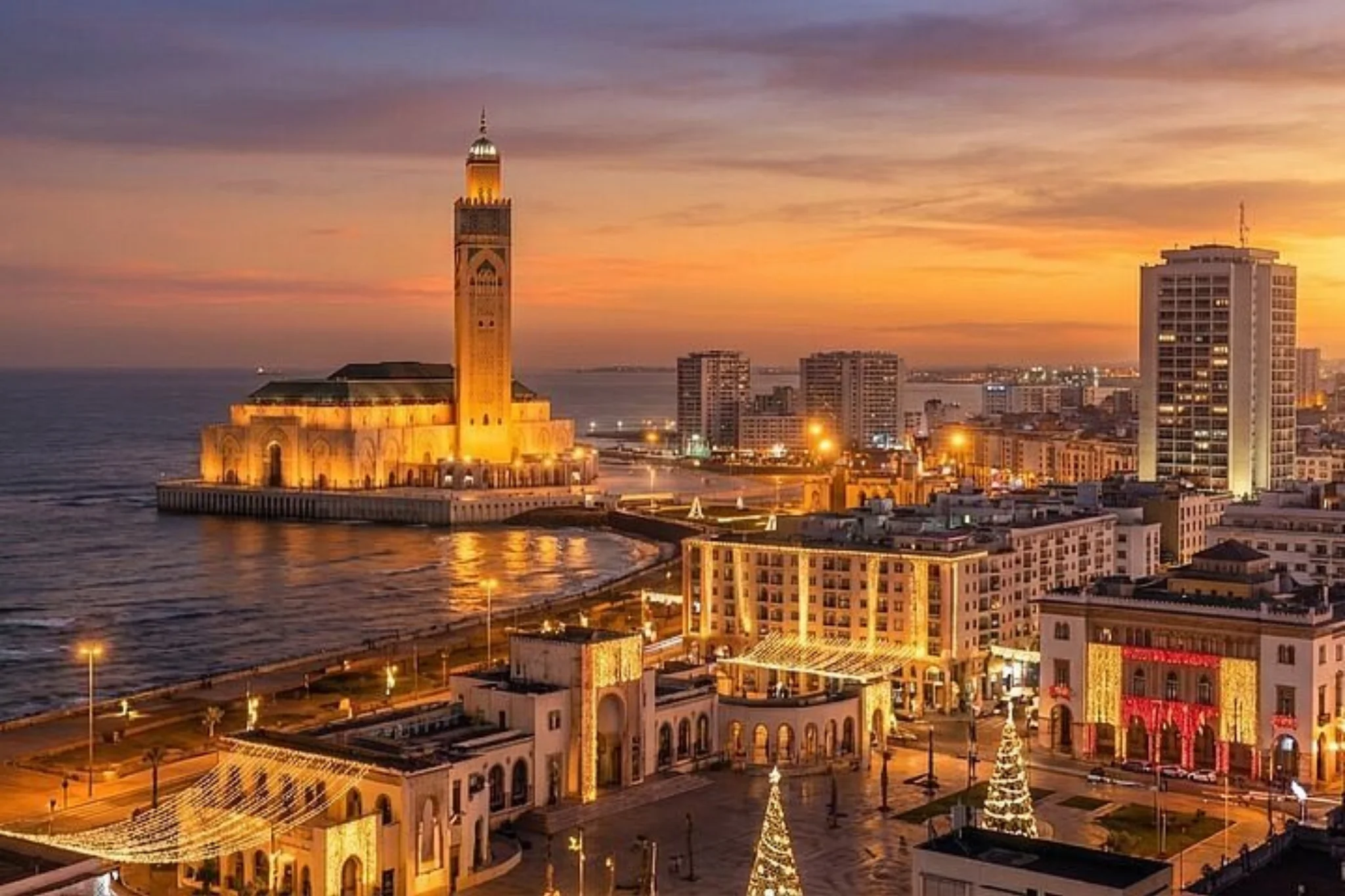 La mosquée Hassan II illuminée au crépuscule face à l'océan à Casa.