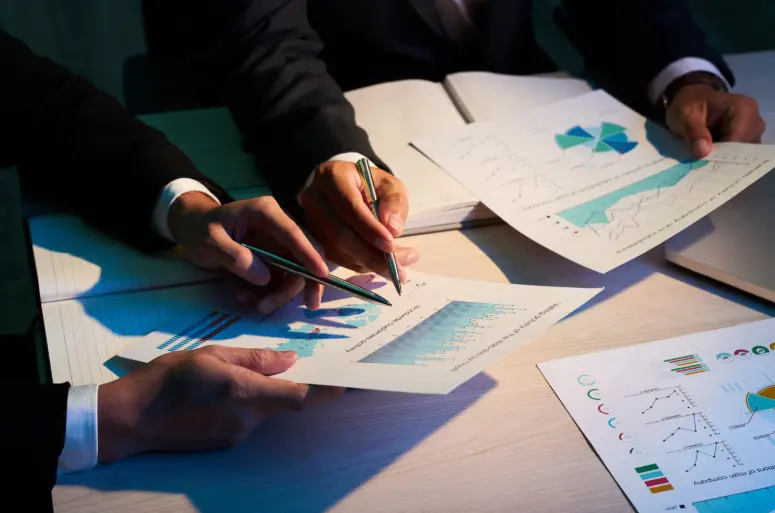 Deux collaborateurs analysant des rapports financiers imprimés.